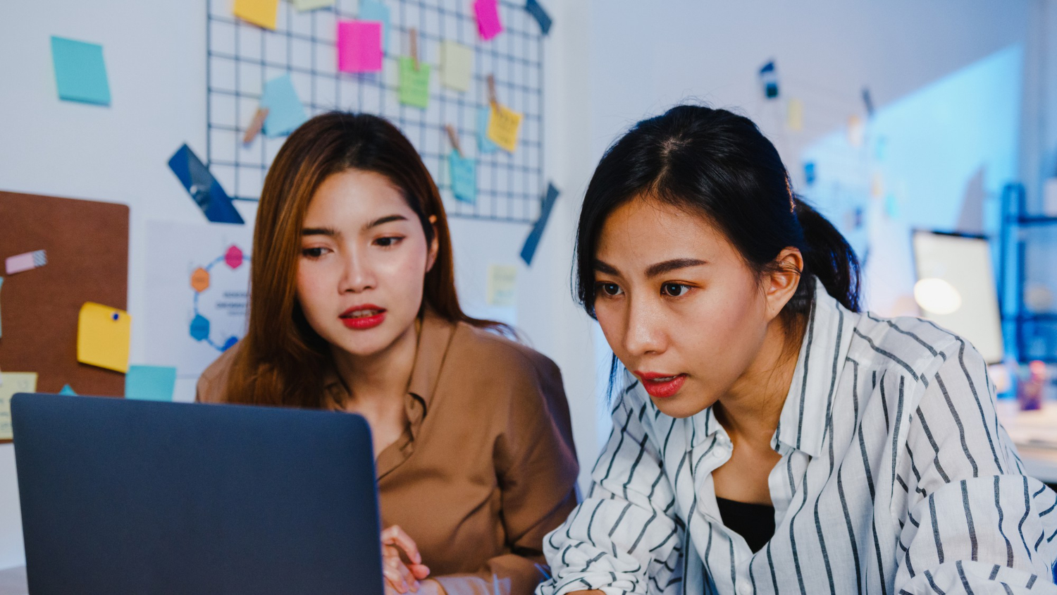 Two colleagues reviewing an HR system on a monitor while planning to automate HR processes